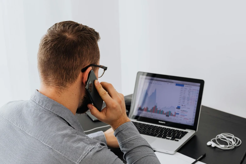 a man sitting at a desk talking on a cell phone, trending on pexels, laptops, lachlan bailey, corporate phone app icon, charts