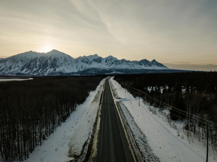 a picture of a road near mountains covered in snow