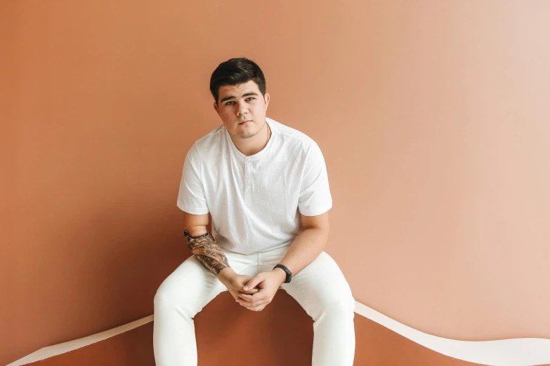 a man sitting on top of a tennis court holding a racquet, an album cover, inspired by Ion Andreescu, pexels contest winner, sitting on a mocha-colored table, dressed in a white t-shirt, full view blank background, halfbody headshot