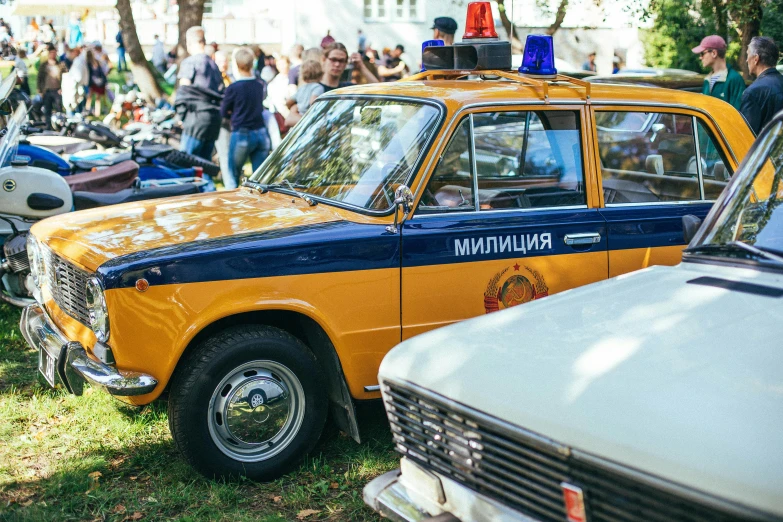 there is an old orange taxi and a motorcycle in the grass