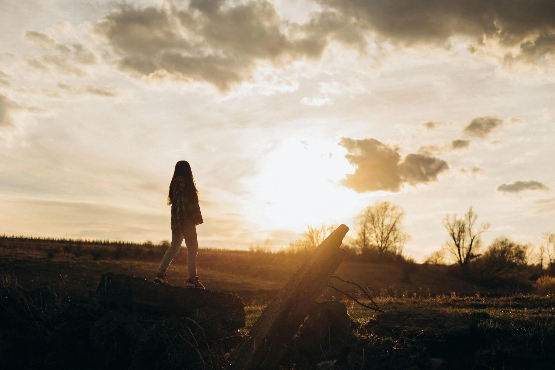 a person walking in the grass while the sun shines down