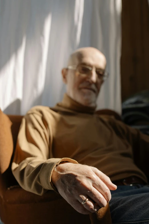 man in a tan shirt sitting in a chair and holding soing