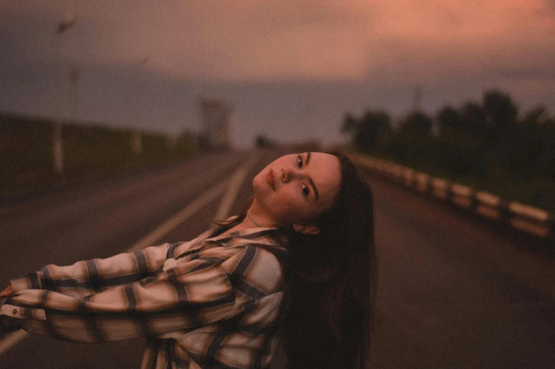 a girl with her eyes closed standing on the side of a road