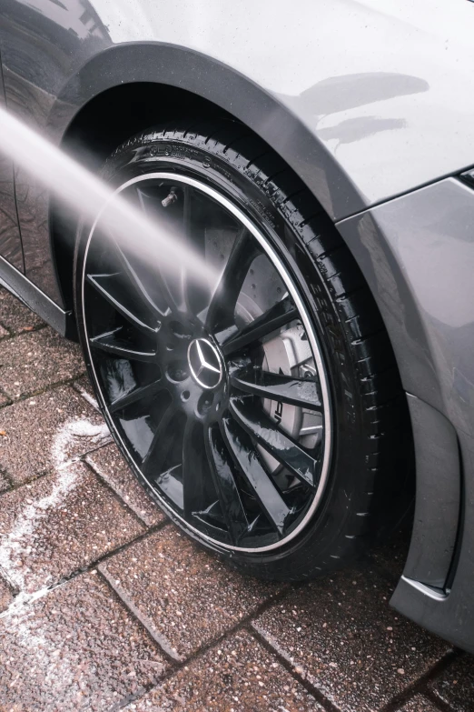 a person washing a car with a high pressure hose, a stipple, by Thomas Häfner, pexels contest winner, black wheel rims, mercedes, 2 0 % pearlescent detailing, black and grey