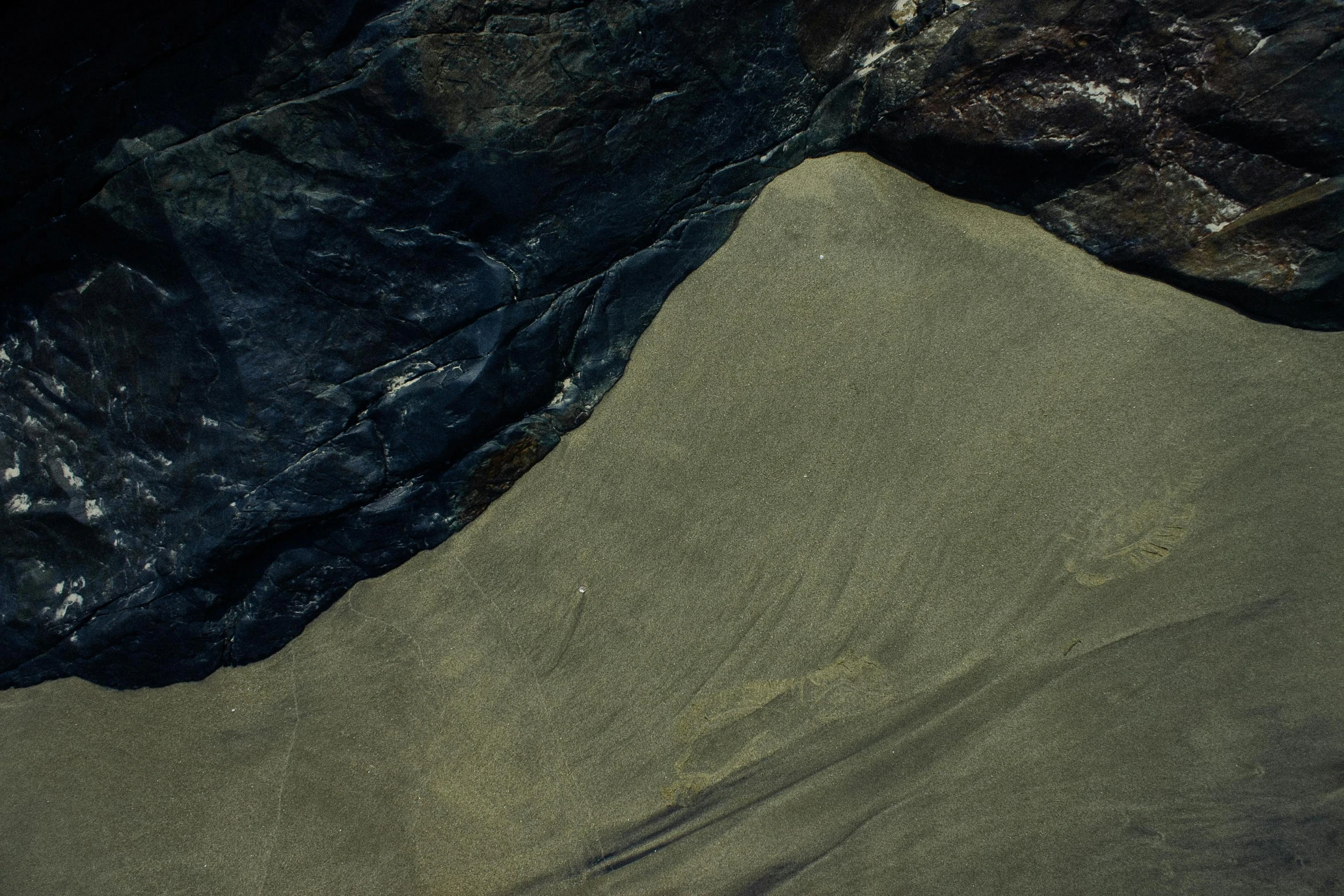 a man riding a surfboard on top of a sandy beach, an album cover, inspired by Andreas Gursky, unsplash contest winner, lyrical abstraction, “ aerial view of a mountain, dark stone, ignant, folds