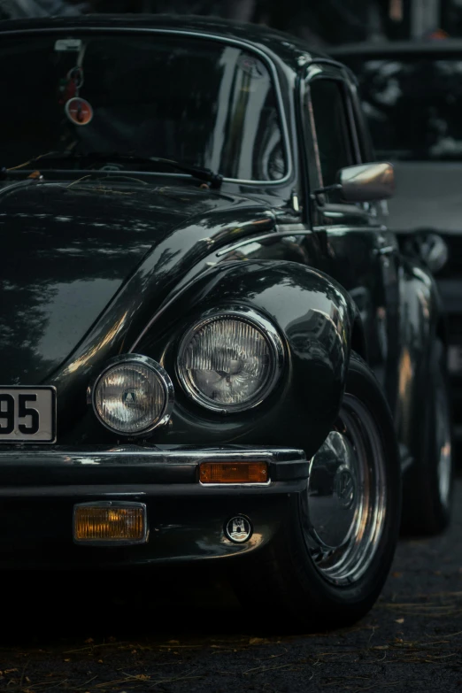 the back view of a classic black vw bug in a parking lot