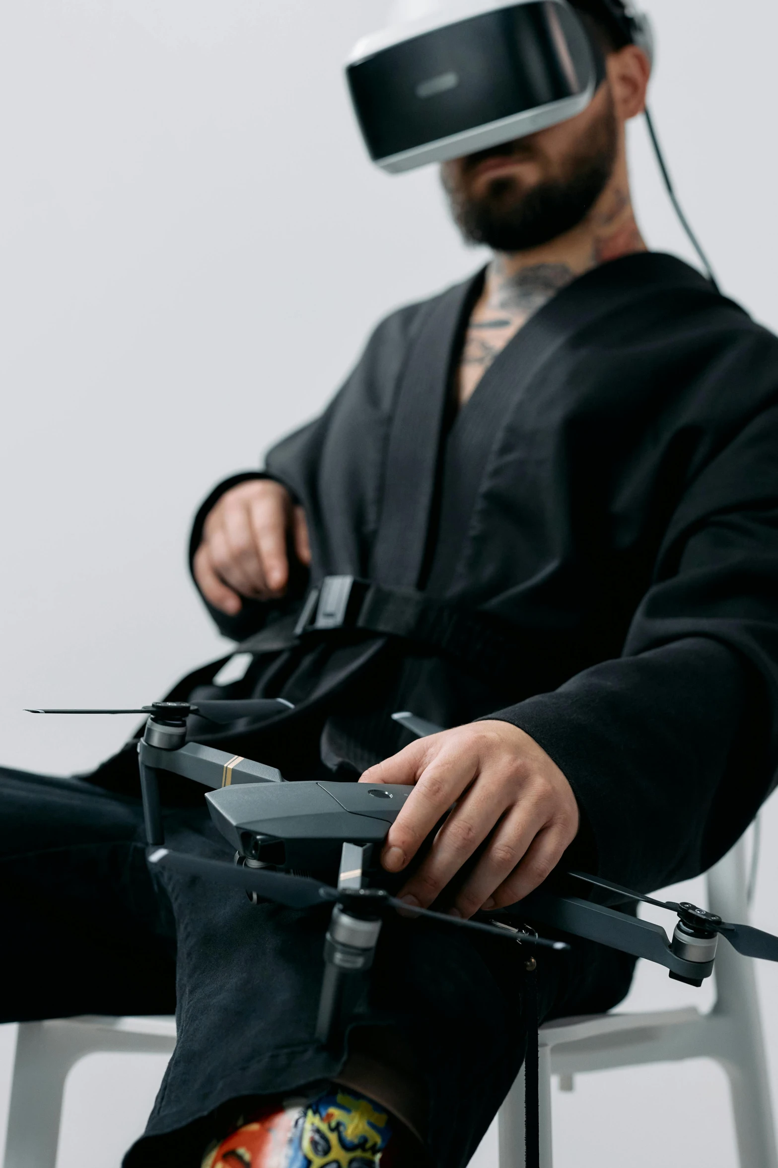 a man sitting on a chair with a remote control in his hand, inspired by Kanō Hōgai, unsplash, renaissance, fighter drones, black robe, upper body close up, low quality photo