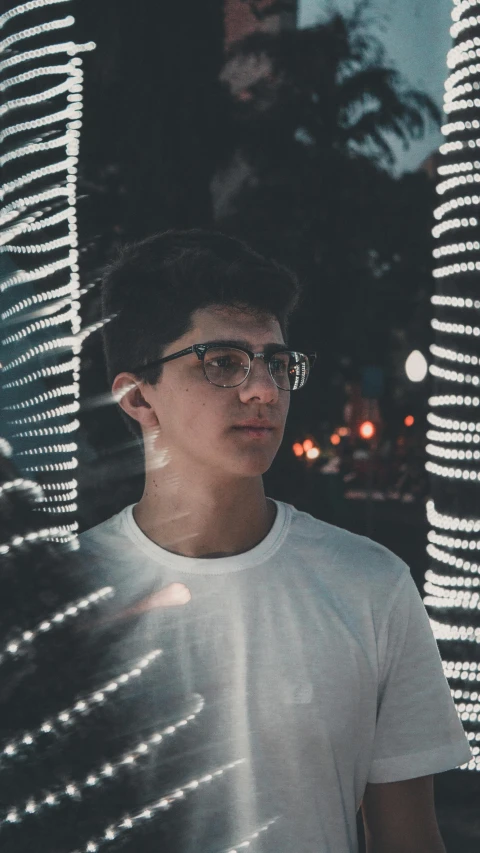 young man standing under lots of lights looking away