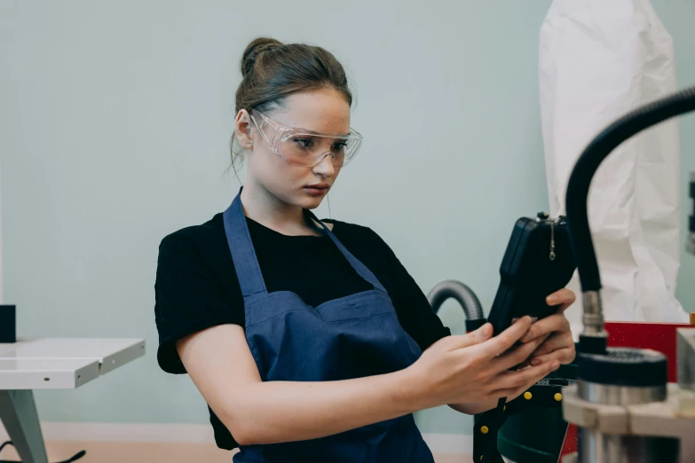 a woman in an apron working on a machine, pexels contest winner, wearing black frame glasses, looking in mirror, avatar image, girl wearing uniform