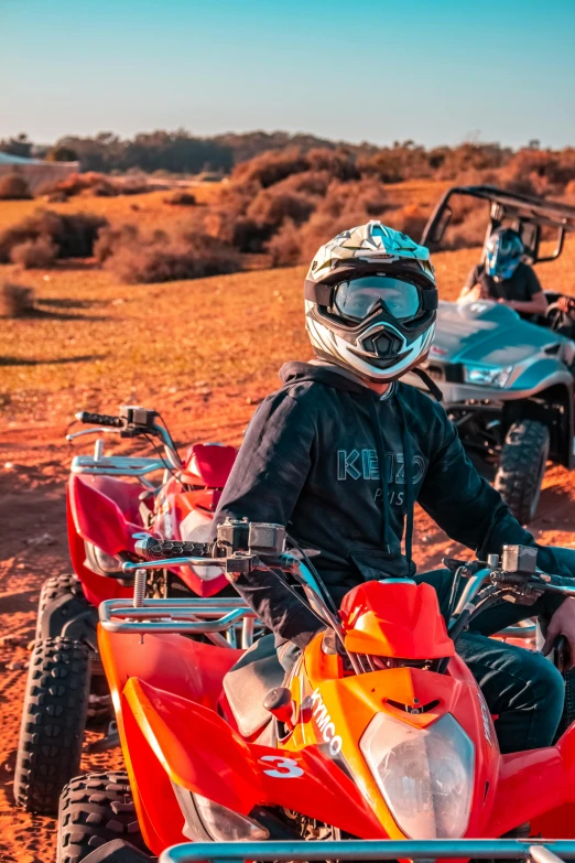 two people sitting on four wheelers in the desert, intense colours, up close, goggles, avatar image