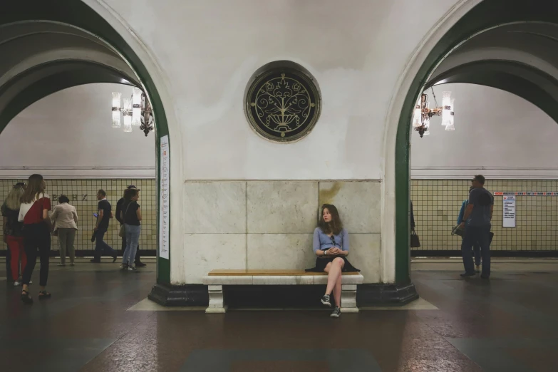 a woman sitting on a bench in a subway station, a photo, rounded ceiling, khreschatyk, emily rajtkowski, uncropped