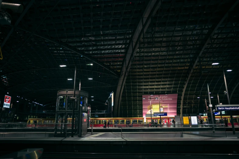 a train station with a train pulling into the station, pexels contest winner, hyperrealism, giant red led screens, black and yellow color scheme, standing in an arena, interior of a small