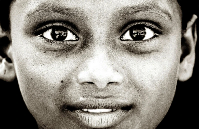 a black and white photo of a young boy, by Sudip Roy, pexels contest winner, hyperrealism, beautiful symmetrical eyes, indian girl with brown skin, face!!!! close - up, many eyes