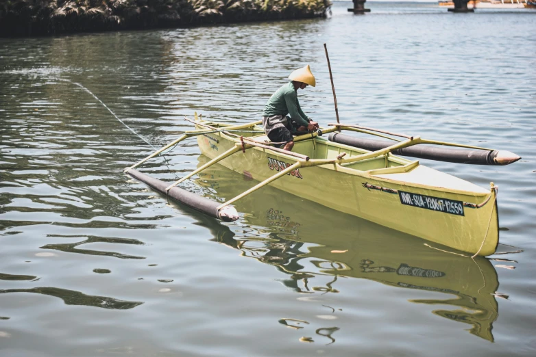 a man in a yellow boat on a body of water, by Jessie Algie, pexels contest winner, mingei, samoan features, working hard, vintage color, 🦩🪐🐞👩🏻🦳