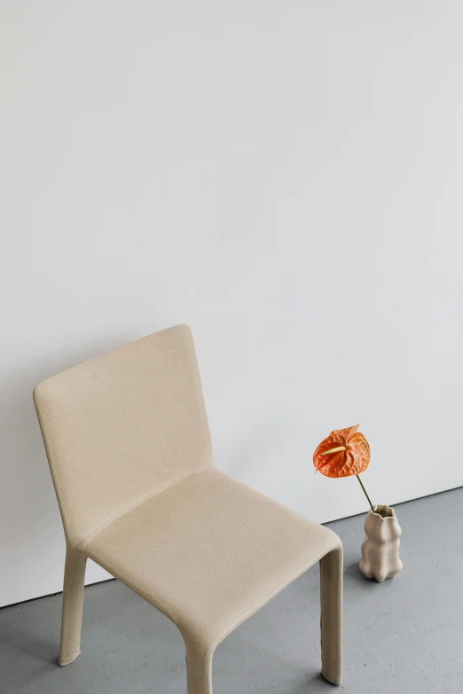 a chair sitting next to a vase with an orange flower in it, inspired by David Chipperfield, minimalism, sand color, - 9