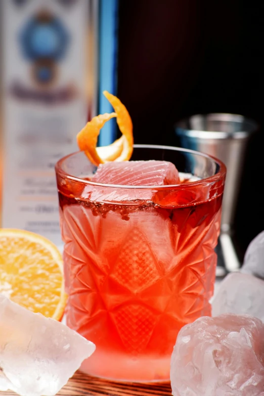 a glass with ice and an orange wedge sitting on the table