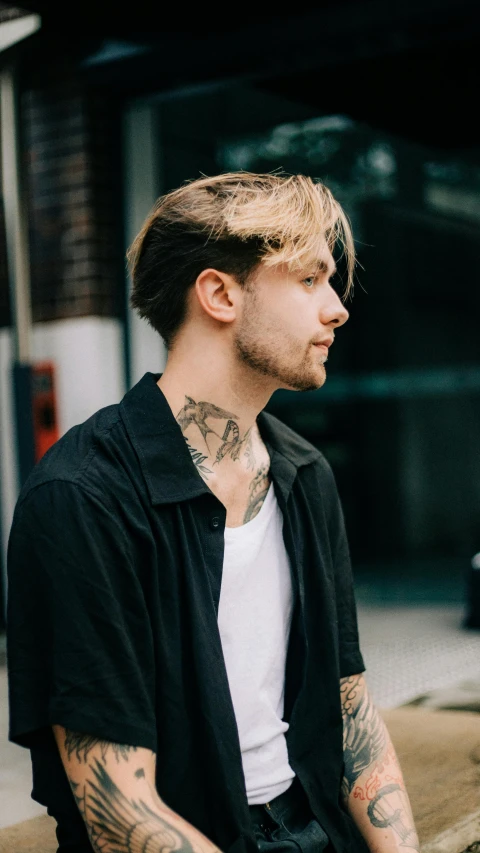 a man with tattoos sitting on a curb