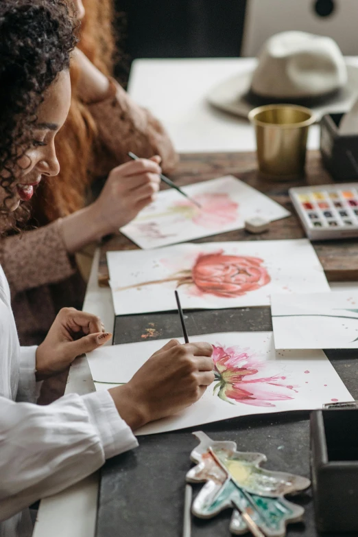 a woman at a table with some paper and painting supplies