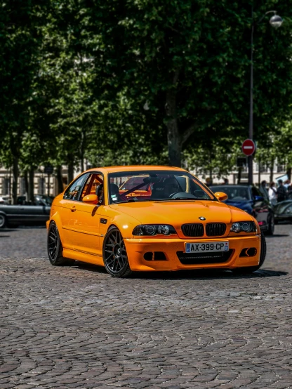 an orange bmw parked in a parking lot next to other cars