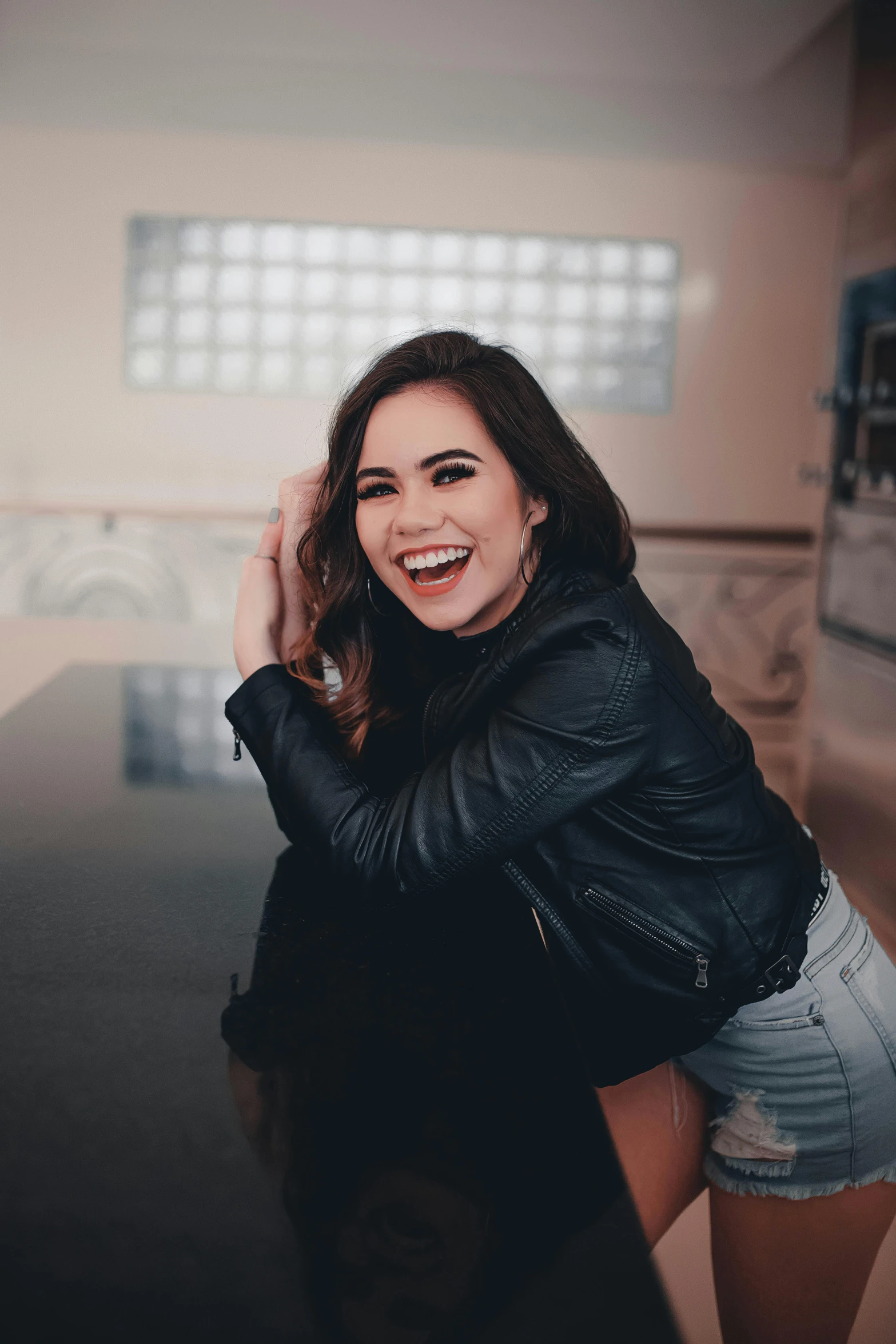 a woman in a black leather jacket and denim skirt