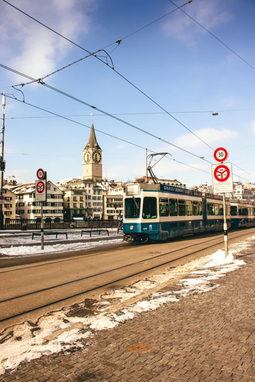 a large long train on a steel track, inspired by Karl Stauffer-Bern, pexels contest winner, art nouveau, city square, sunny winter day, three towers, traffic signs