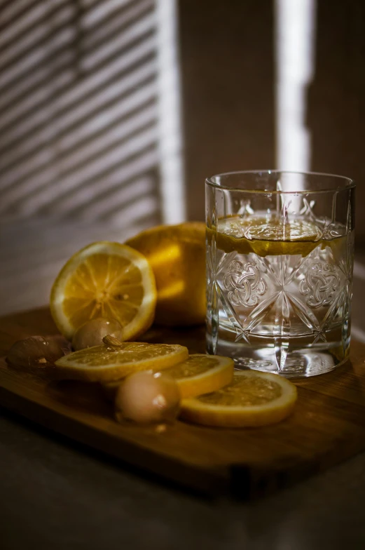 a glass of whiskey sitting on top of a wooden cutting board, a still life, inspired by Jesper Knudsen, unsplash, peeled lemons, photographed for reuters, 1900's, grey