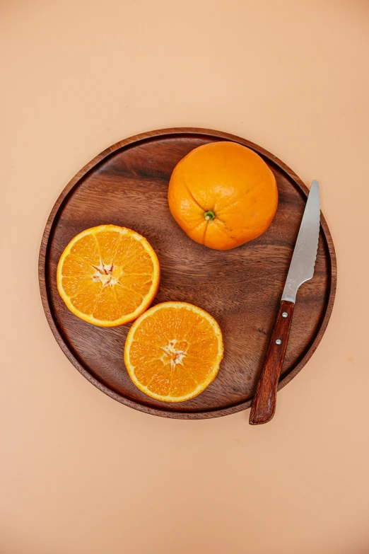 an orange sitting on top of a cutting board next to a knife, on a wooden plate, full product shot, sleek round shapes, detailed product image