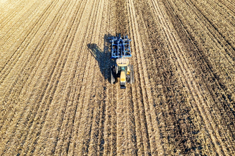 an aerial view of a tractor plowing a field, by Jeffrey Smith, pexels, precisionism, worksafe. instagram photo, 1 6 x 1 6, brown, vertical orientation