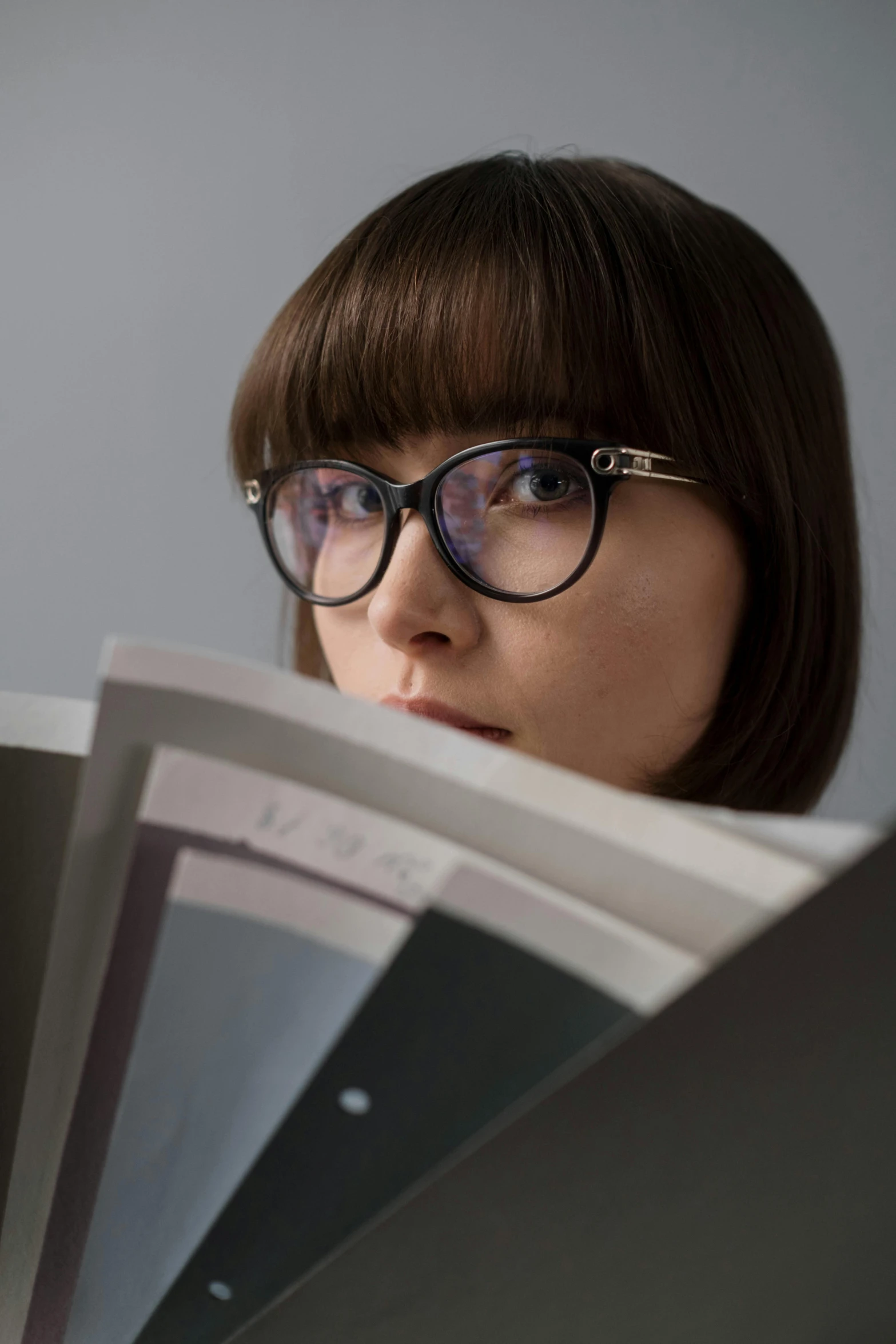 a woman reading a book while wearing glasses, a picture, inspired by Kanō Naizen, trending on unsplash, academic art, square glasses, shocked, fashion magazines, photographed for reuters