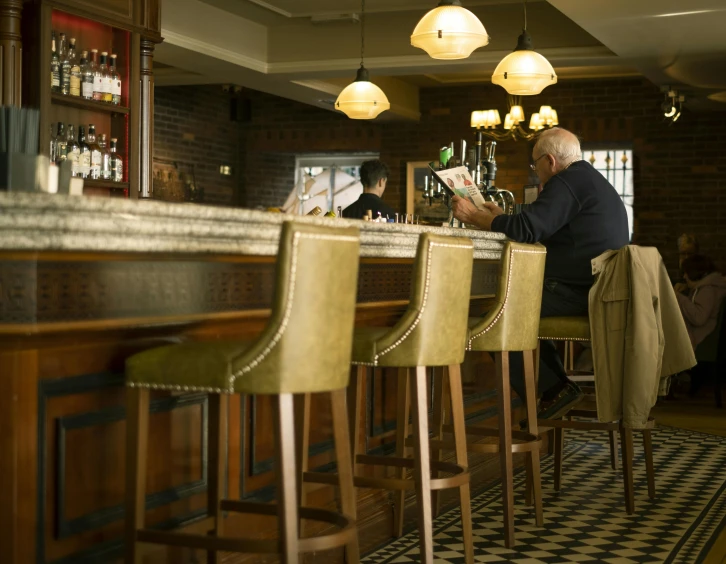 a man in an establishment drinking a drink and reading