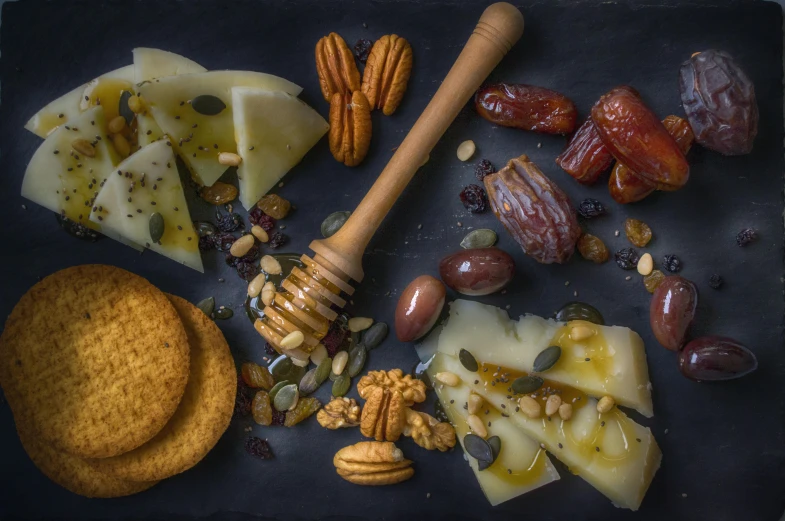 a black plate topped with cheese, crackers and nuts, inspired by Francisco Josè de Goya, pexels contest winner, honey, harvest, background image, middle eastern