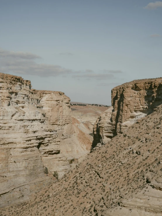 a couple of people standing on top of a cliff, les nabis, brown canyon background, some zoomed in shots, trending on vsco, between sedimentary deposits
