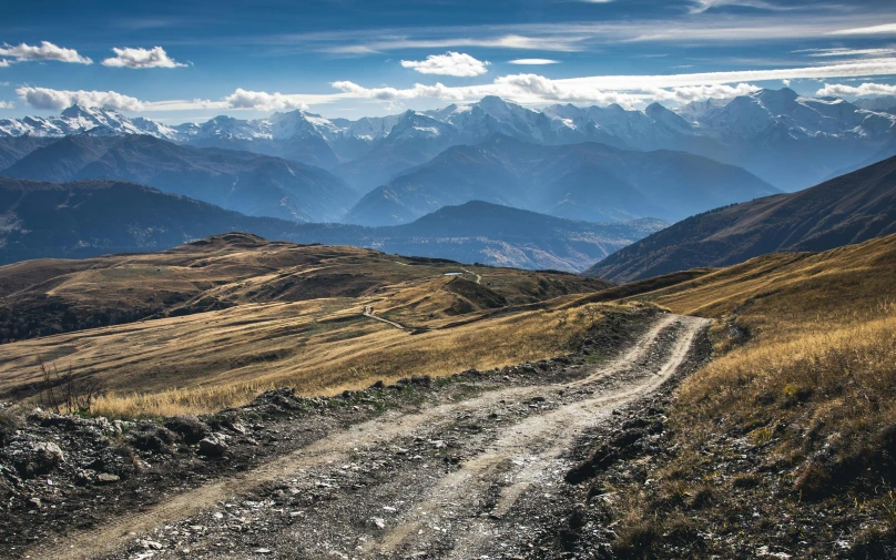 a dirt road winding into the distance with mountains in the background