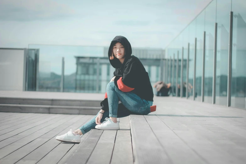 a woman sitting on top of a wooden floor, a picture, pexels contest winner, realism, wearing jeans and a black hoodie, chinese girl, avatar image, candid photography