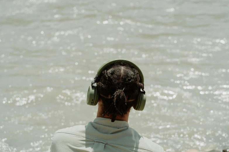 a person sitting in the water with headphones on, hurufiyya, seen from afar, 5k, looking off into the distance, diverse