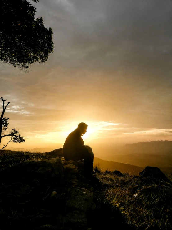 a person sitting on top of a hill at sunset, profile image