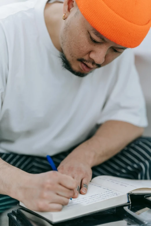 a man writes with a blue pen on a note book