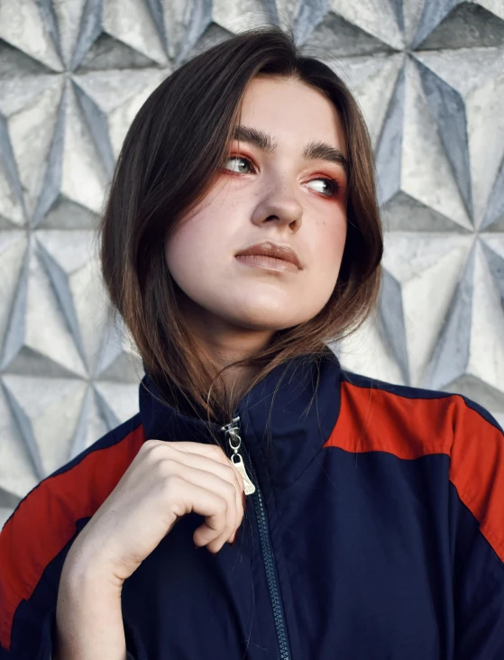 a young woman in an orange, navy, and black windbreaker