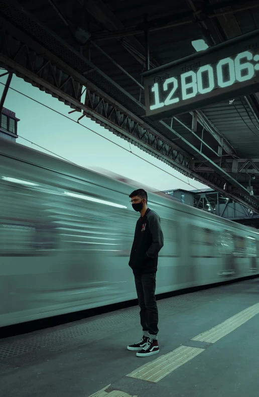 a man standing in front of a train at a train station, an album cover, pexels contest winner, wearing facemask, trending on artstattion, profile pic, deep in thought