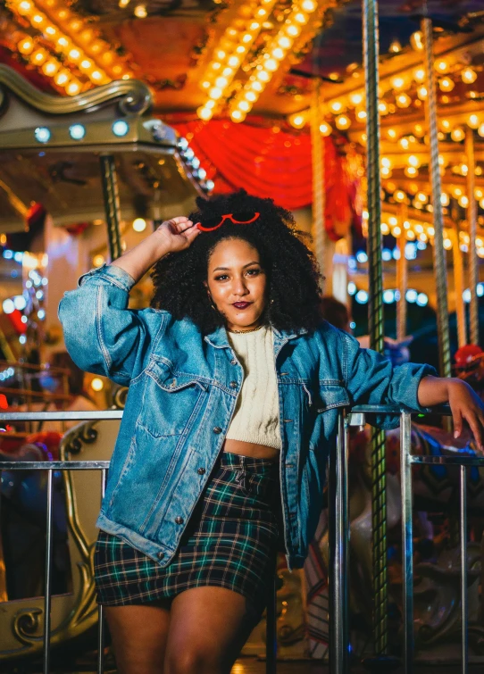 a woman standing in front of a carousel at night, an album cover, trending on unsplash, kitsch movement, wearing a jeans jackets, curls and curves, flannel, posing for a picture