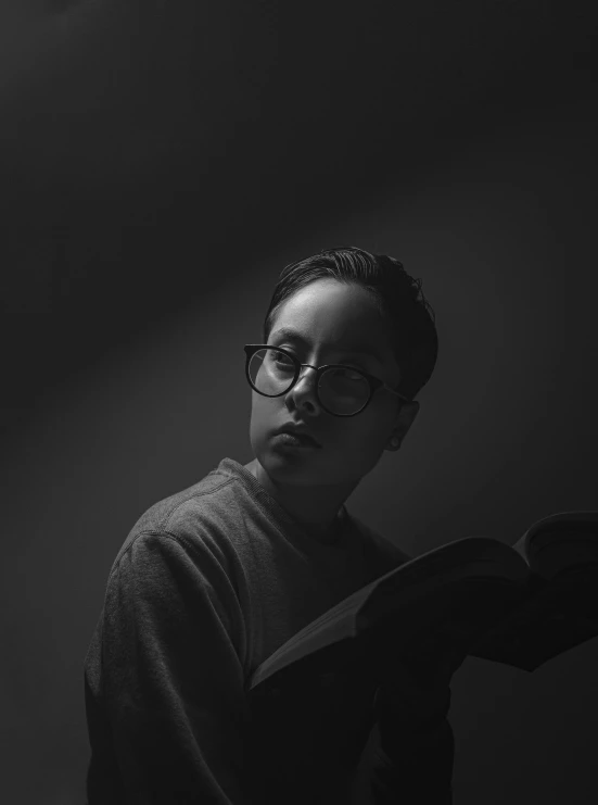 a black and white photo of a man with glasses, by Andrew Domachowski, unsplash contest winner, portrait androgynous girl, dramatic reading book pose, portrait of 1 5 - year - old boy, ariel perez