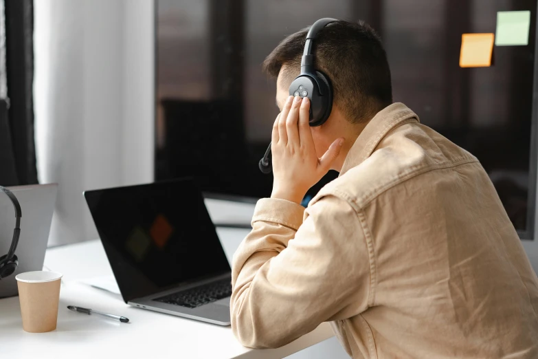 a man sitting at a desk with a laptop and headphones, trending on pexels, hurufiyya, royal commission, thumbnail, background image, working in a call center