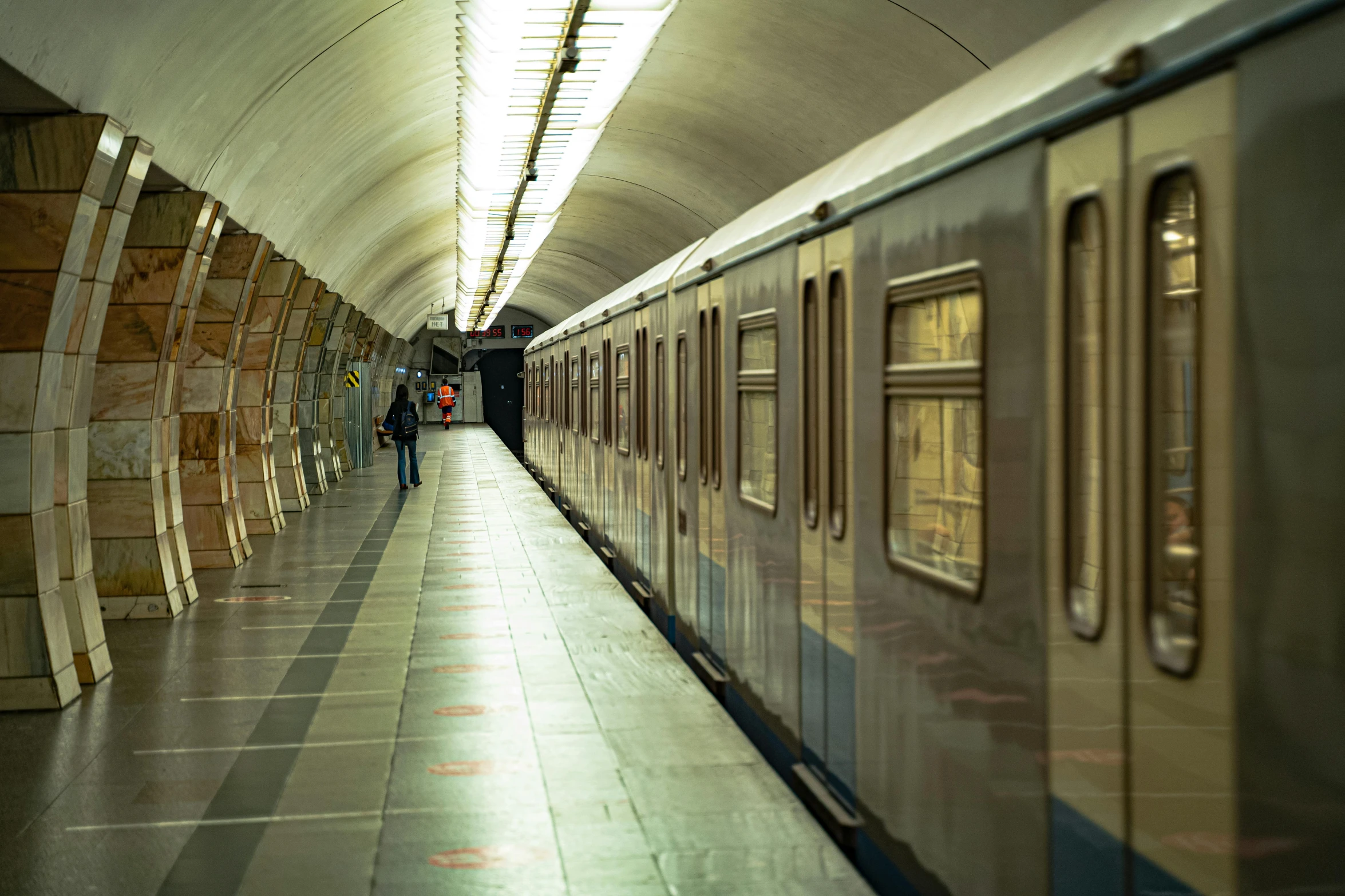 a subway train stopped with a person walking down the platform