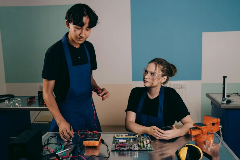 a couple of people that are sitting at a table, arbeitsrat für kunst, electronic circuitry, high school, high-quality photo, lachlan bailey