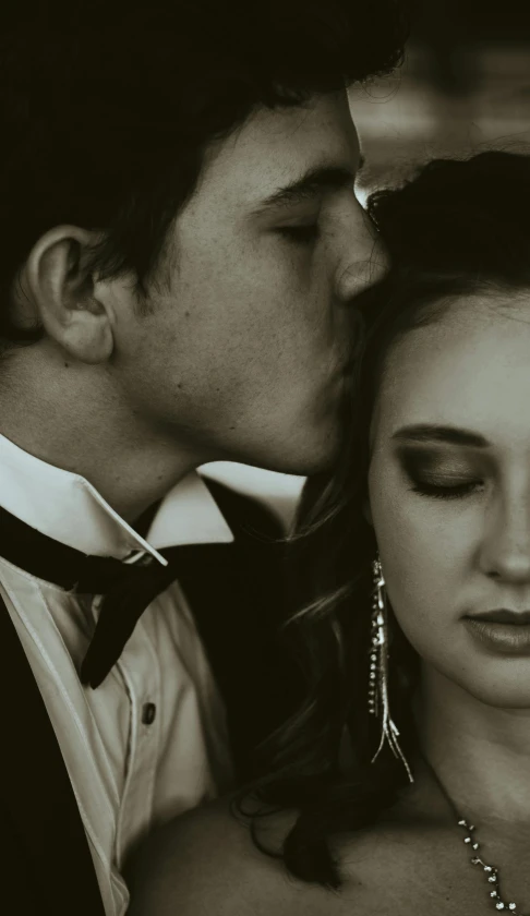 a black and white photo of a man kissing a woman, a black and white photo, by Ryan Pancoast, trending on pexels, renaissance, formal attire, closeup 4k, high school, video