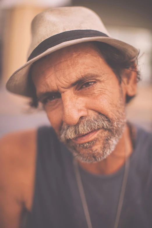 man with mustache and hat on sitting on concrete