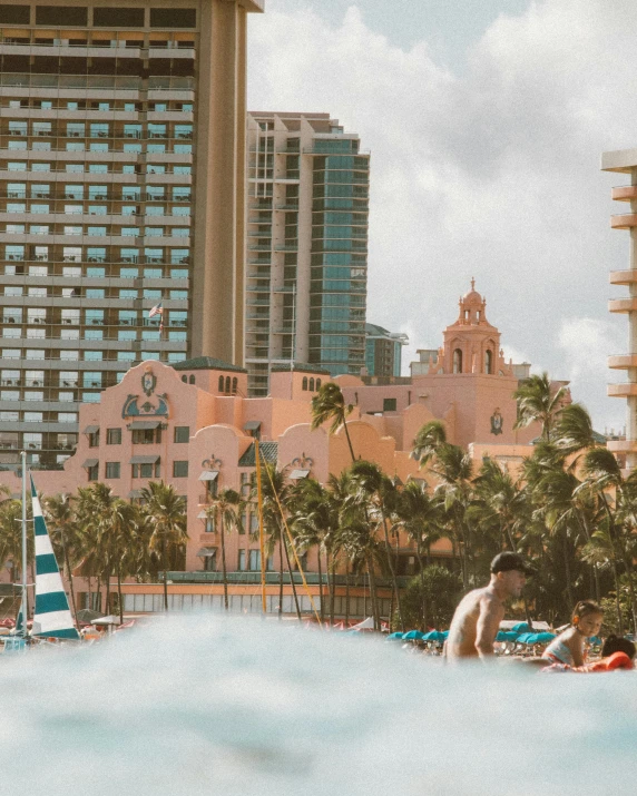 people lounge in a el pool with sailboats and palm trees in the background