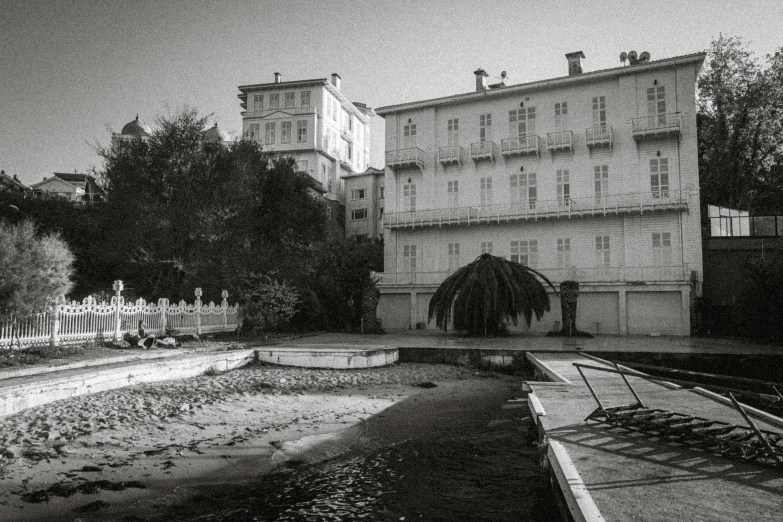 a black and white photo of a building next to a body of water, a black and white photo, unsplash, art nouveau, next to a pool, abandoned streets, monaco, abandoned hospital