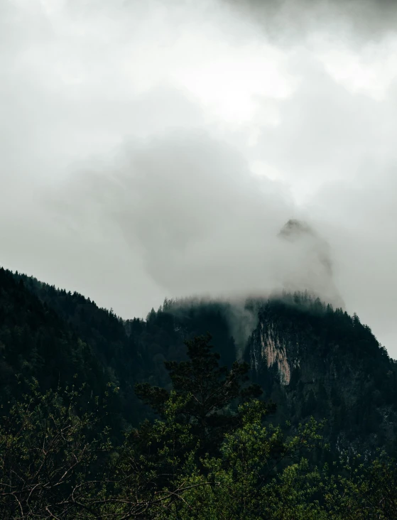 a very high mountain in the clouds on a cloudy day