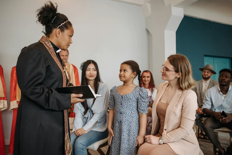 a group of people standing and sitting in a room, holy ceremony, mixed race, profile image, woman holding another woman